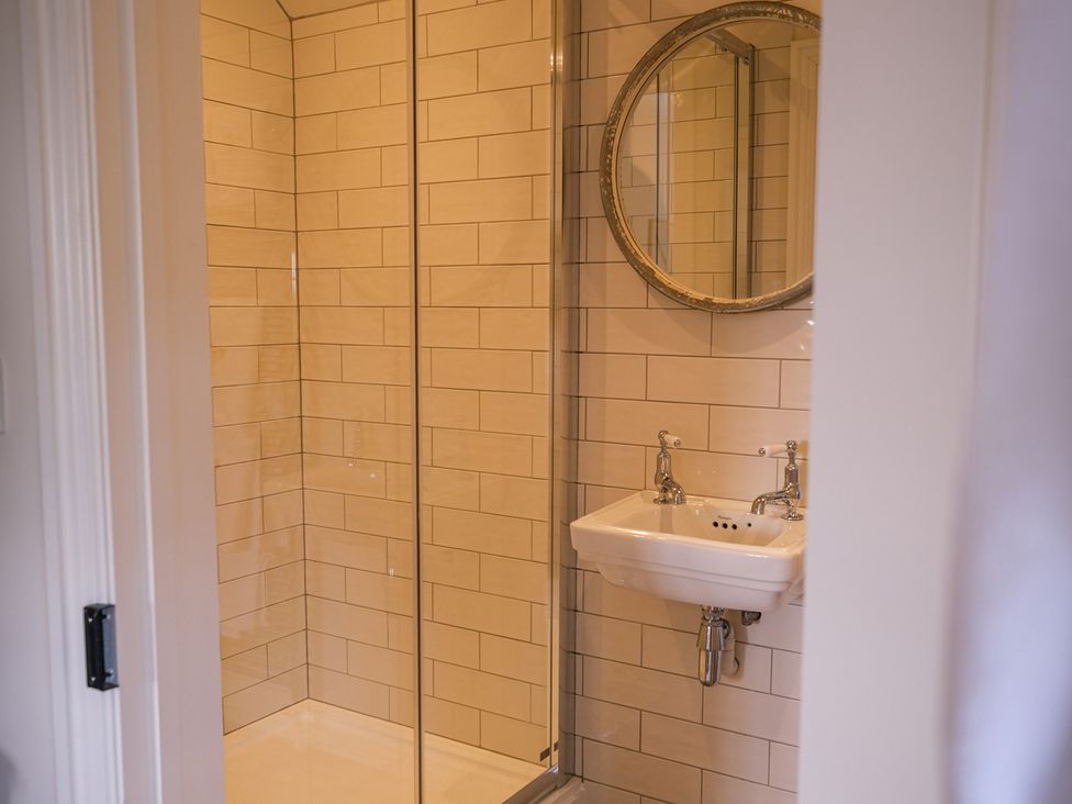 A bathroom featuring a shower, sink, and mirror at Challens Yarde in Midhurst