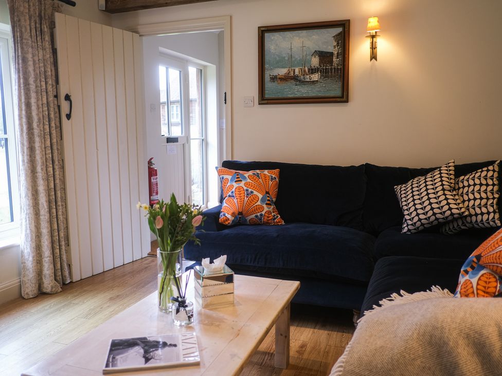 A living room with a sofa and a vase of flowers at Heathe End Lodsworth near Eastbourne