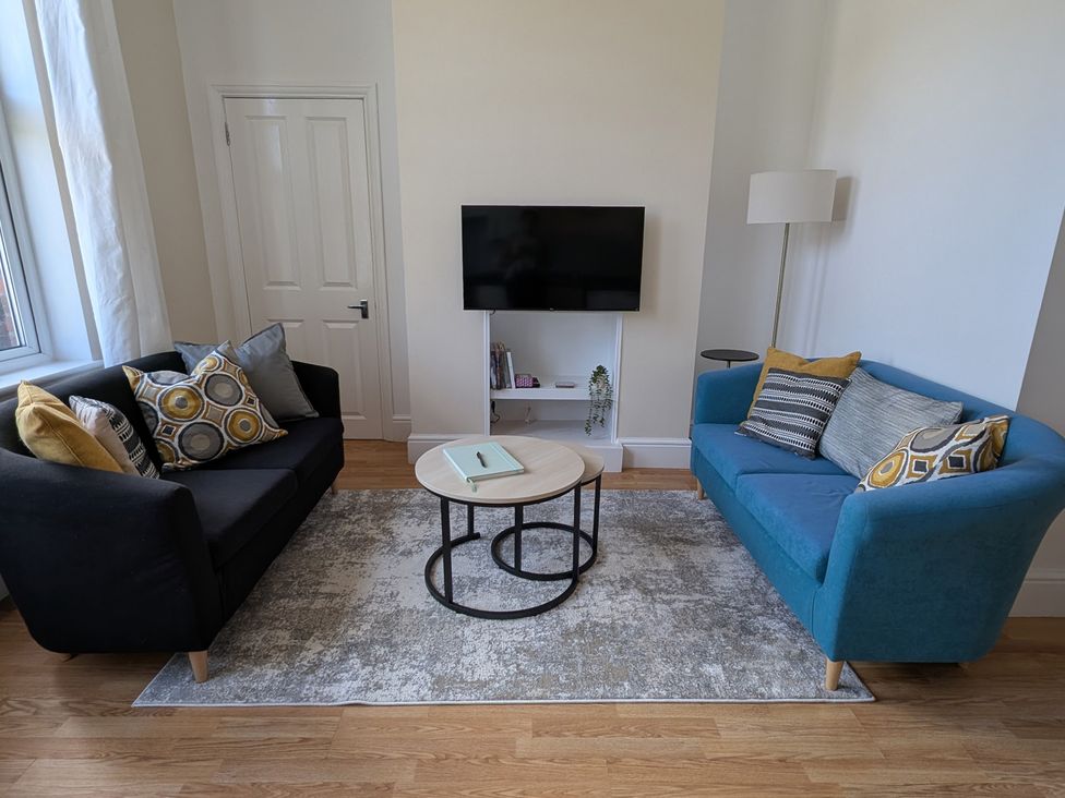 A living room with sofas, a coffee table, and a television at Flat 3 in Poole