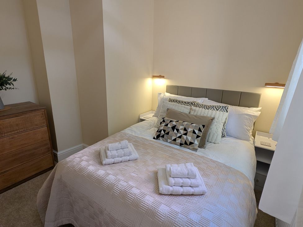 A bedroom with a bed, dresser, and bedside lamps at Flat 3 in Poole