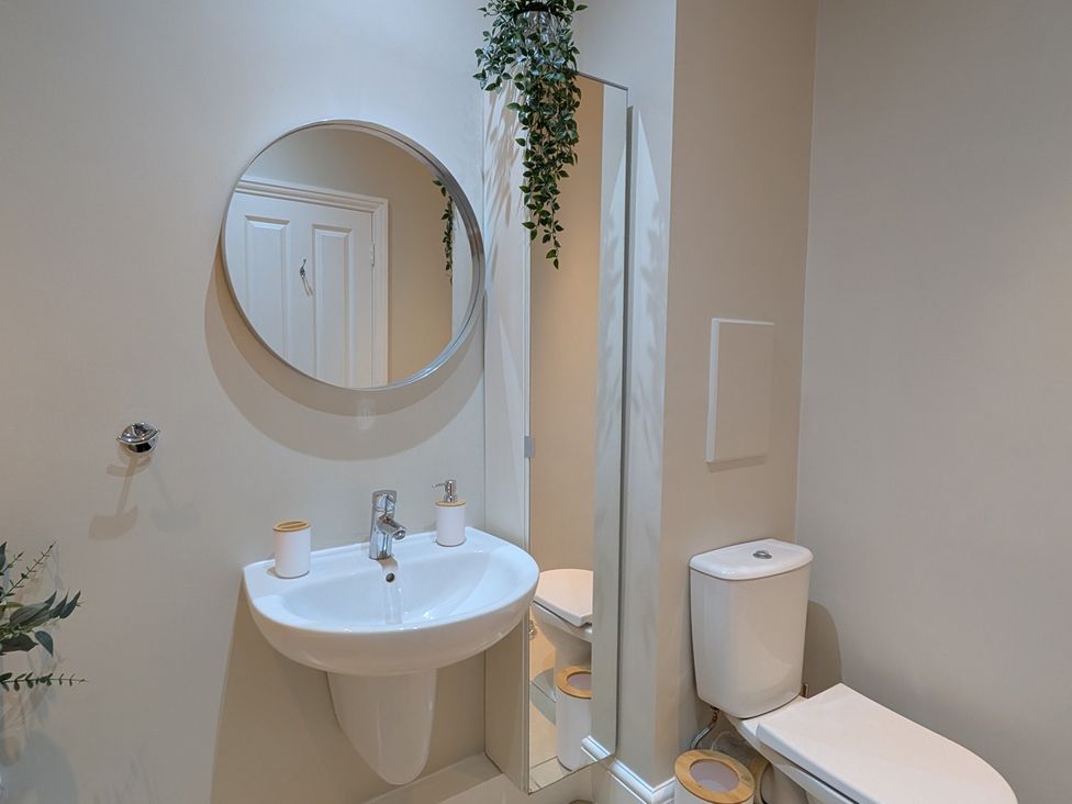 A bathroom with a sink, toilet, and mirror at Flat 3 in Poole