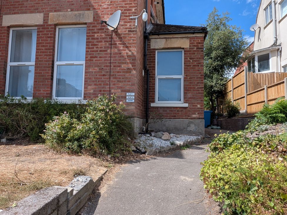 An outdoor area featuring a path, bushes, and a brick wall at Flat 3 in Poole