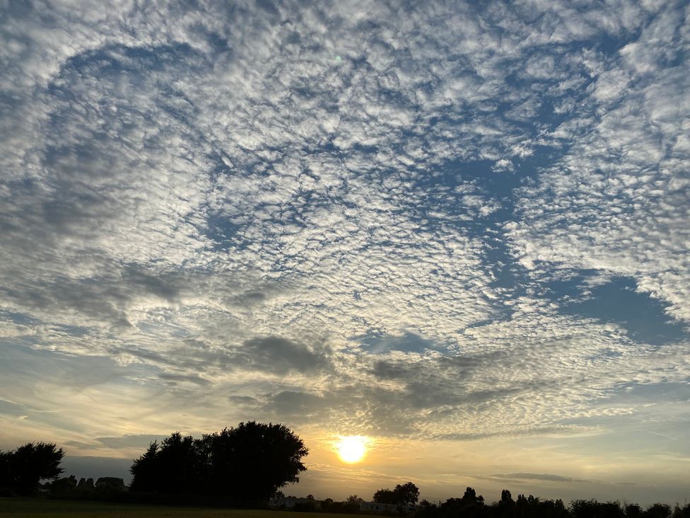 A sunset with clouds and trees in the background at Oakwood Annexe Colchester