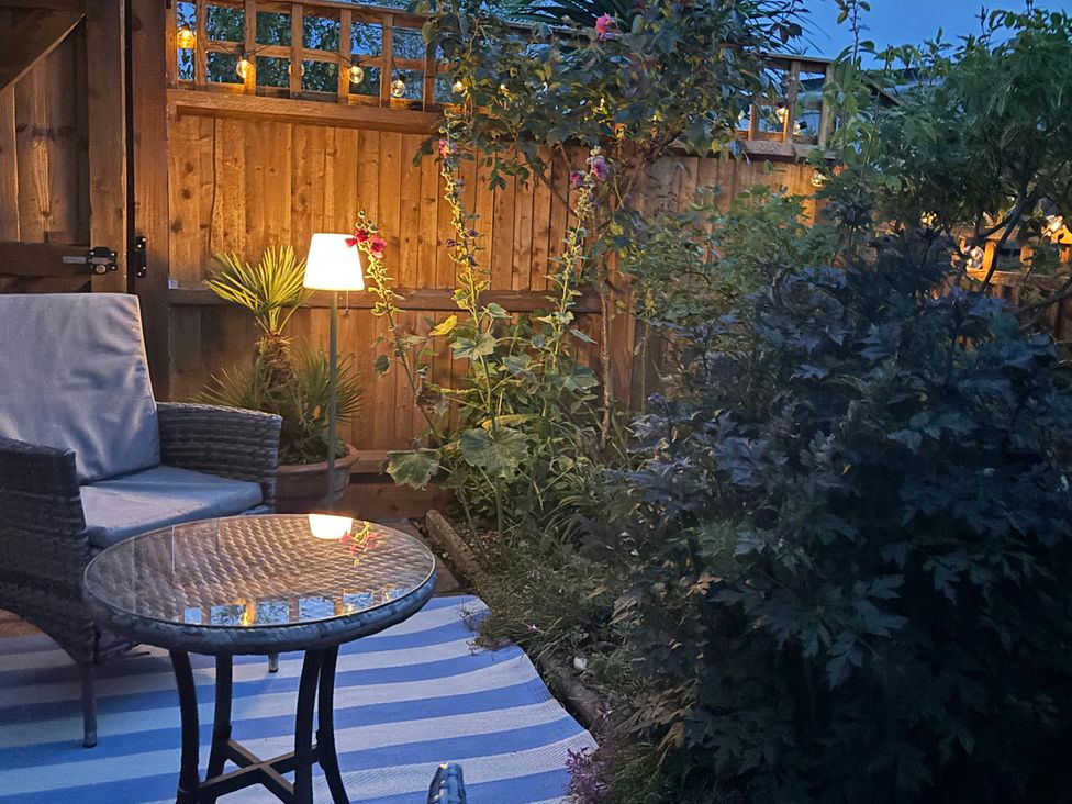 A garden with a chair and table near plants and a lamp at Oakwood Annexe in Colchester