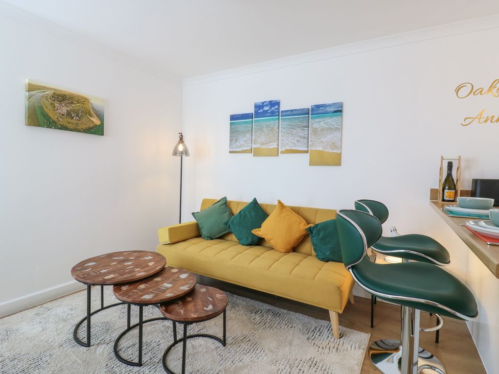 A living room with a yellow sofa and coffee tables at Oakwood Annexe in Colchester