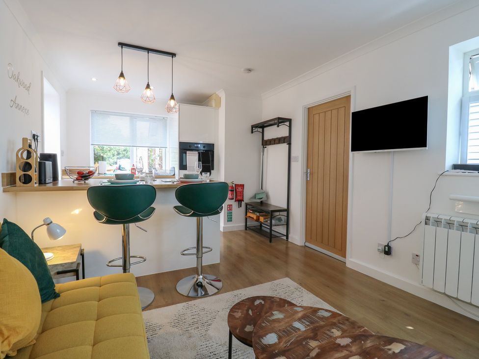 A kitchen area with bar stools and a dining table at Oakwood Annexe Colchester