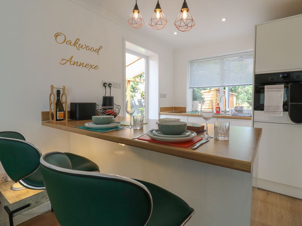 A kitchen with a counter and bar stools at Oakwood Annexe in Colchester