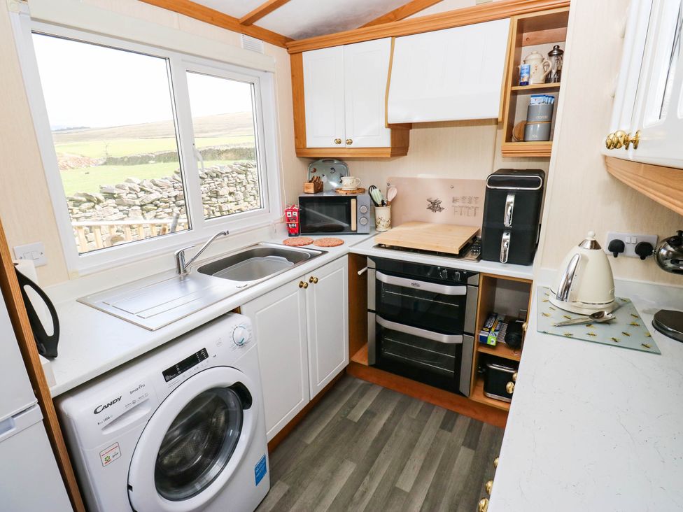 A kitchen with a washing machine and microwave at Lodge in High Peak
