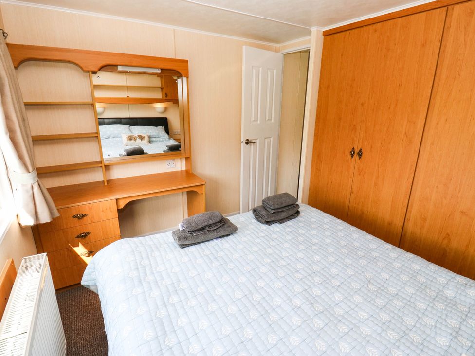 A bedroom with a bed and a mirrored dresser at Lodge in High Peak
