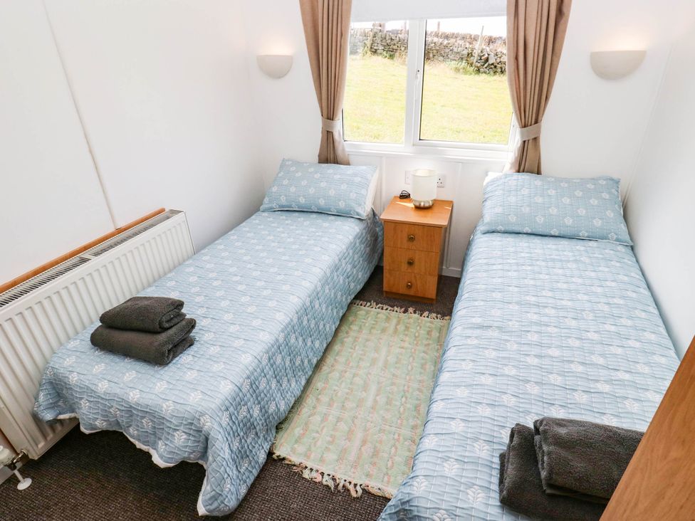 A bedroom with two single beds and a nightstand at Lodge in High Peak