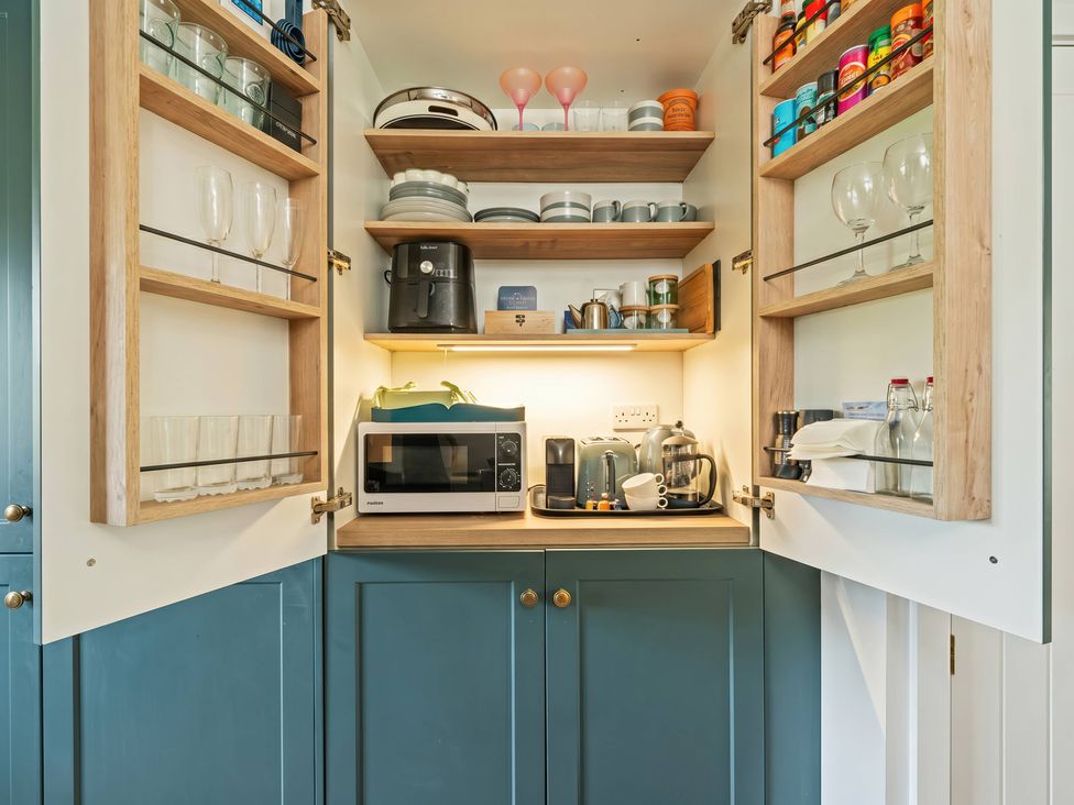 A kitchen cabinet with microwave and various kitchenware at TBC 