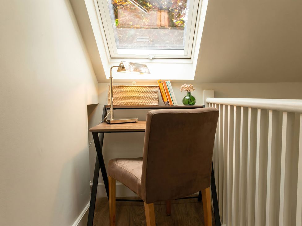 A study area with a desk, chair, lamp, and books at TBC