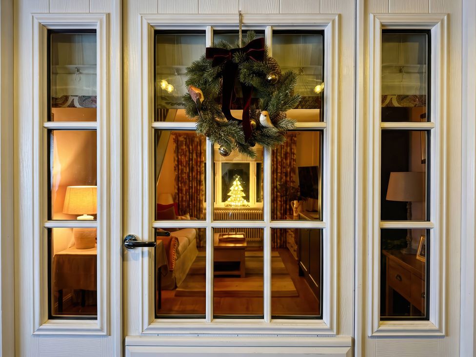 A view of a living room through a door adorned with a wreath at TBC 