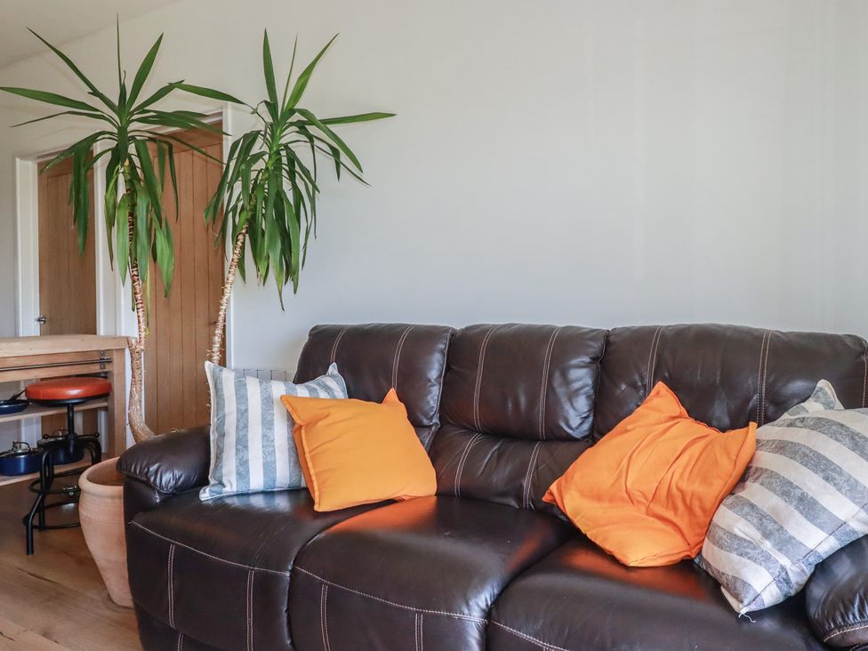 A living room with a sofa and plants at Rollies Retreat in Fowey