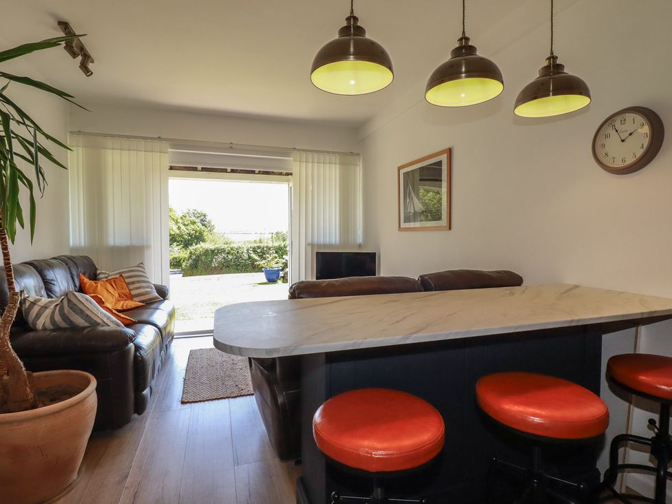 A living room with a sofa and bar stools at Rollies Retreat in Fowey