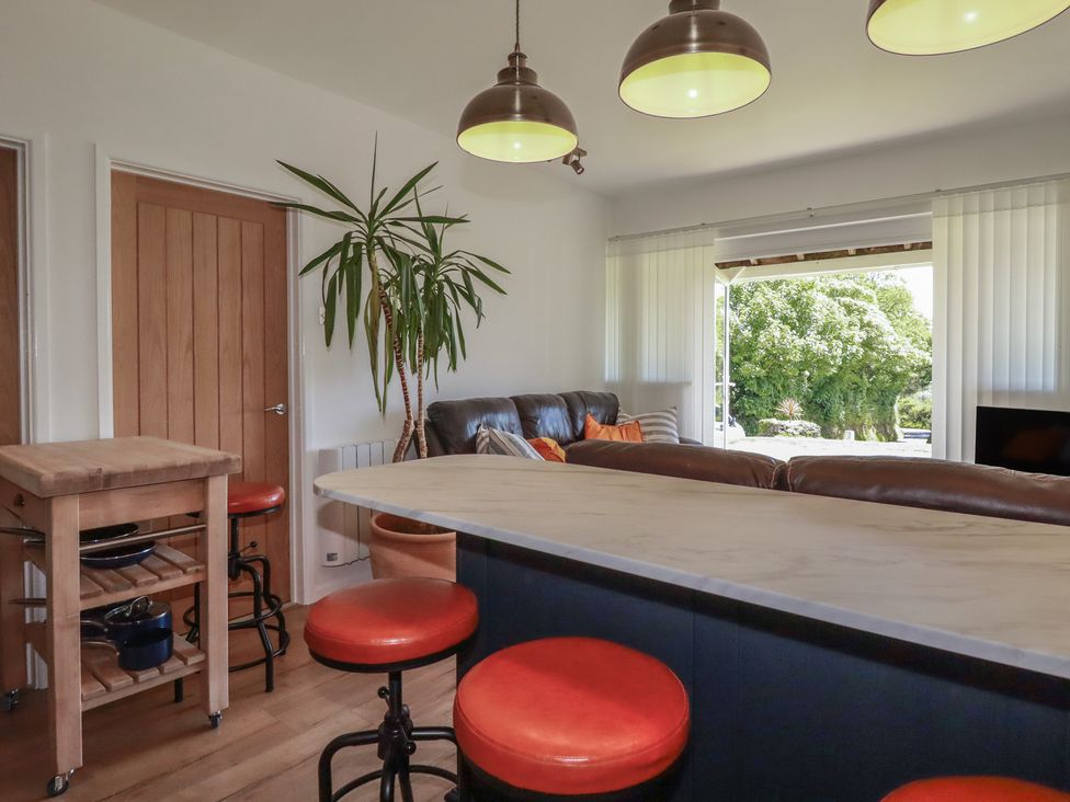 A living room with a sofa and bar stools at Rollies Retreat in Fowey