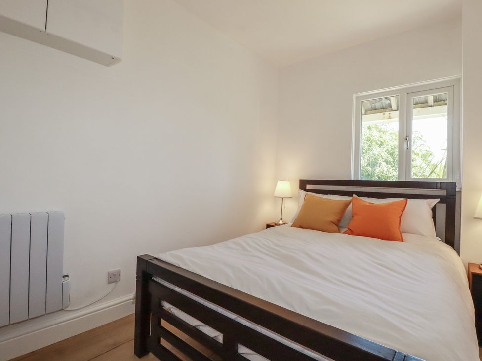 A bedroom with a bed and window at Rollies Retreat Fowey