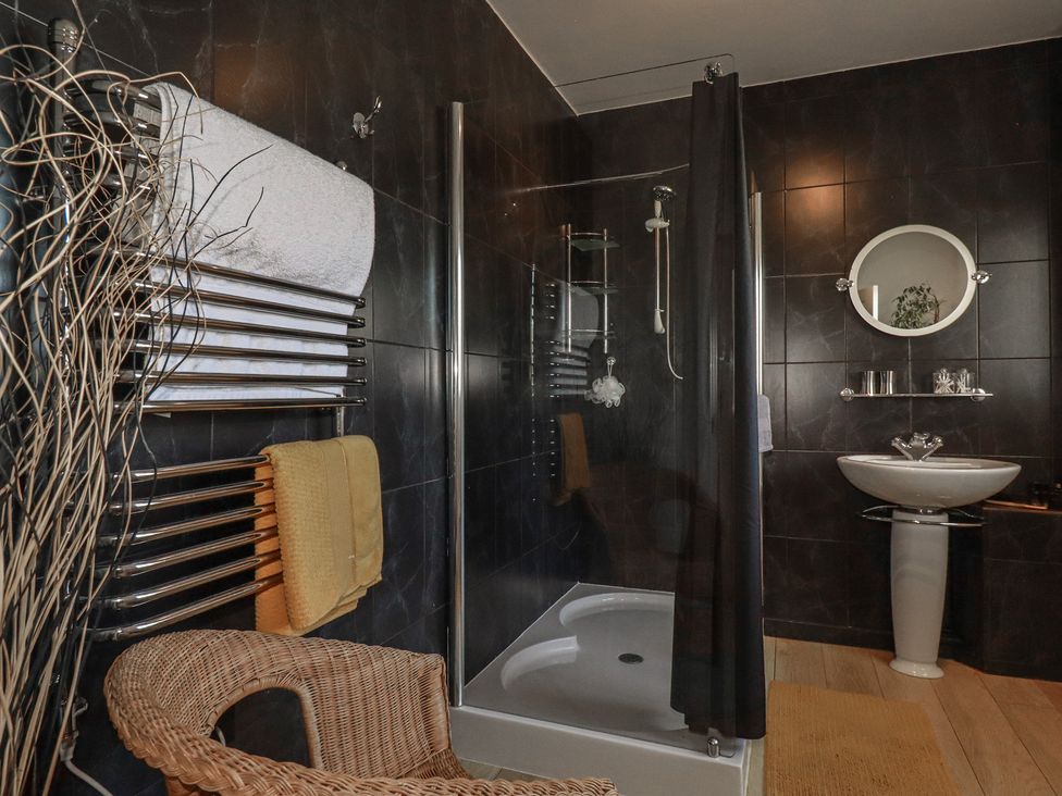 A bathroom with a shower and towel rack at Rollies Retreat in Fowey