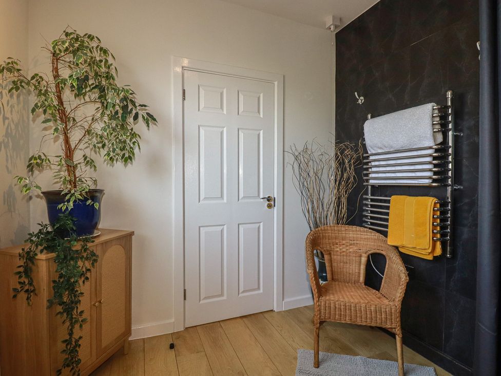 A bathroom with a chair and plants at Rollies Retreat in Fowey