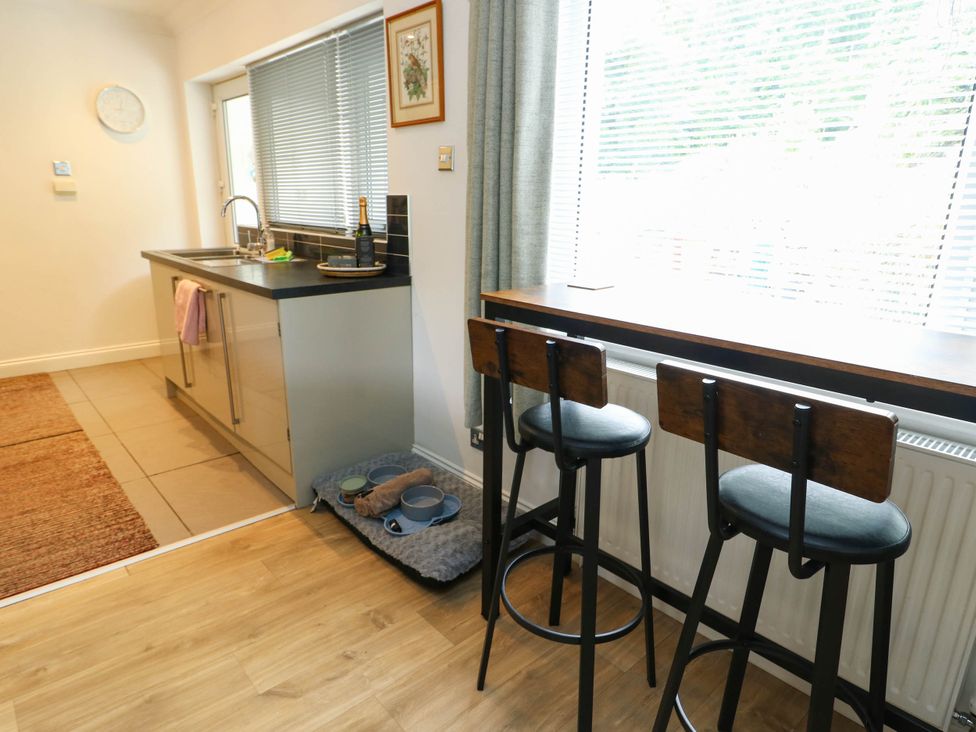 A kitchen with bar stools and a sink at Dyffryn in Betws-Y-Coed