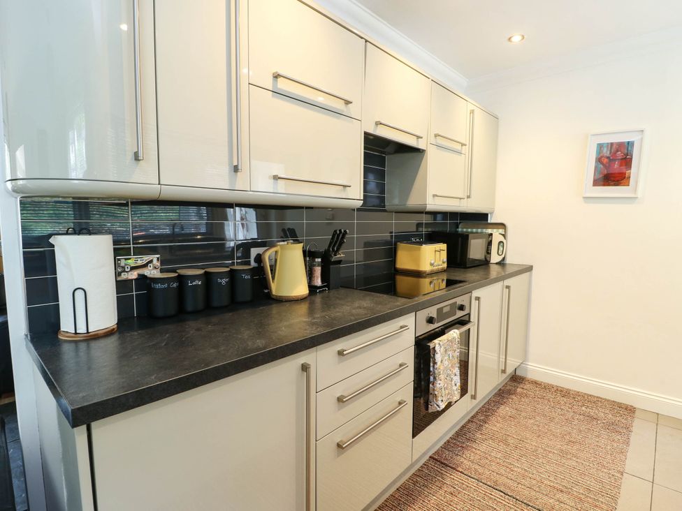 A kitchen with cabinets, countertop, kettle, toaster, and microwave at Dyffryn in Betws-Y-Coed