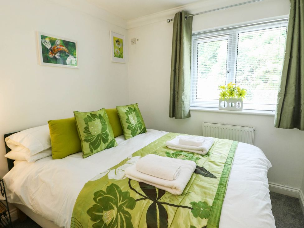 A bedroom with a bed and cushions at Dyffryn Betws-Y-Coed