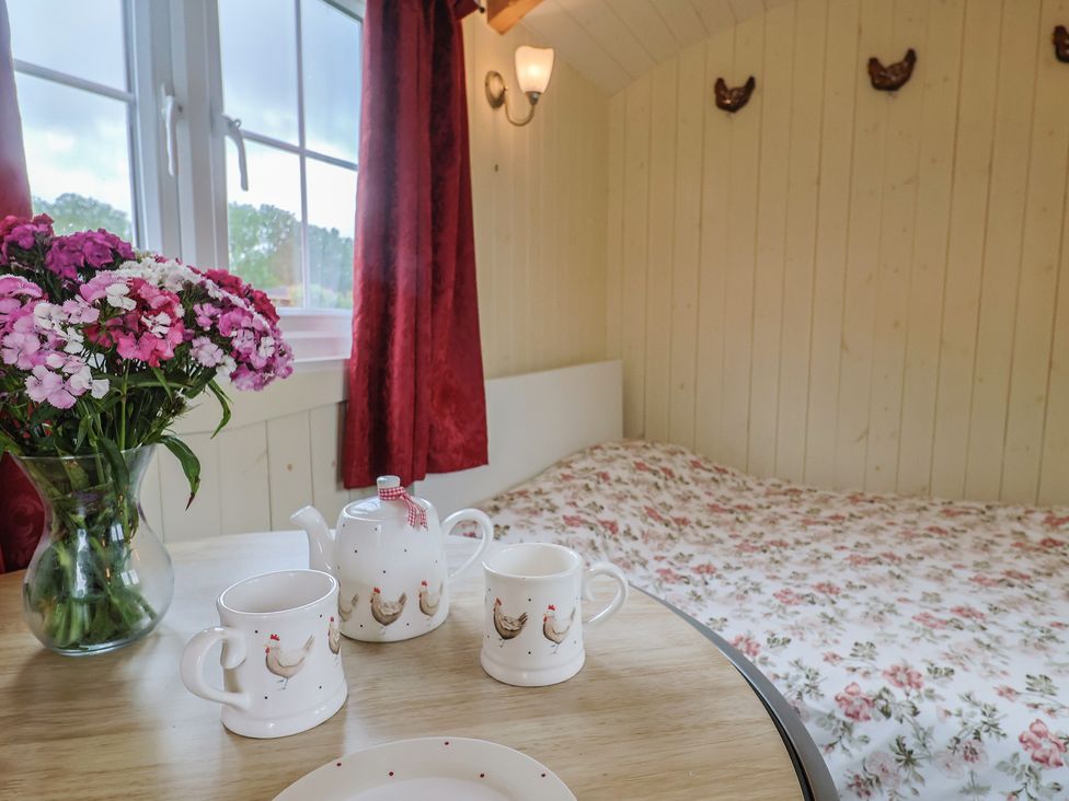 A bedroom with a table set for tea and a floral bedspread at Shepherds Hut at East Hill Pride Four Elms Hill Nr. Sidmouth