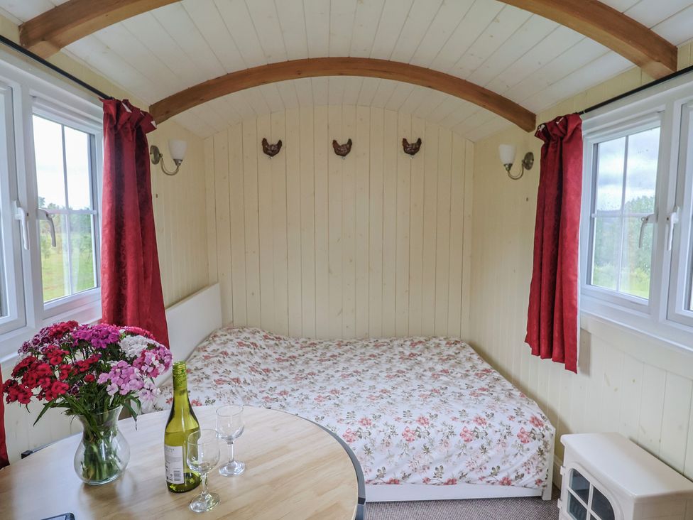 A bedroom with a bed and table with wine at Shepherds Hut at East Hill Pride Four Elms Hill Nr. Sidmouth