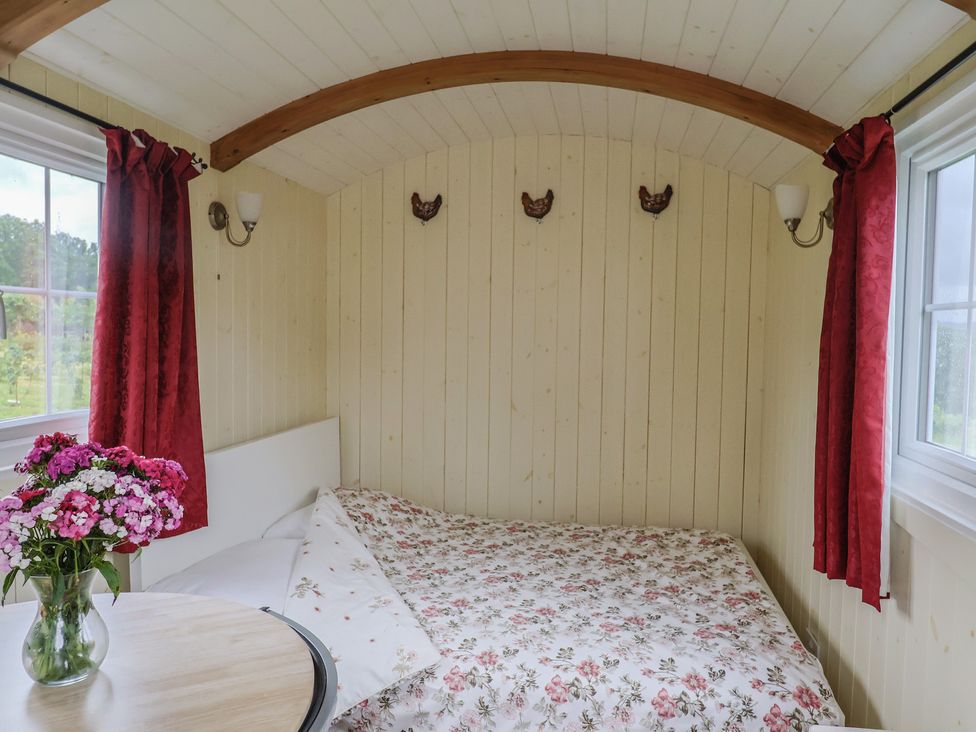 A bedroom with a bed and table at Shepherds Hut at East Hill Pride Four Elms Hill Nr. Sidmouth