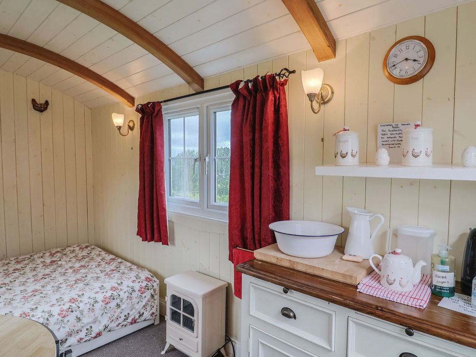 A bedroom with a bed, window, and shelf at Shepherds Hut at East Hill Pride, Four Elms Hill Nr. Sidmouth