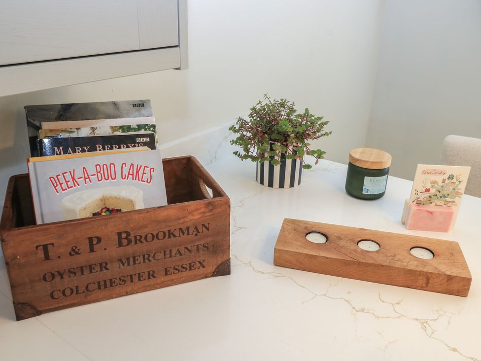 A kitchen with books in a wooden box and a potted plant at 2 The Gardens Lechlade