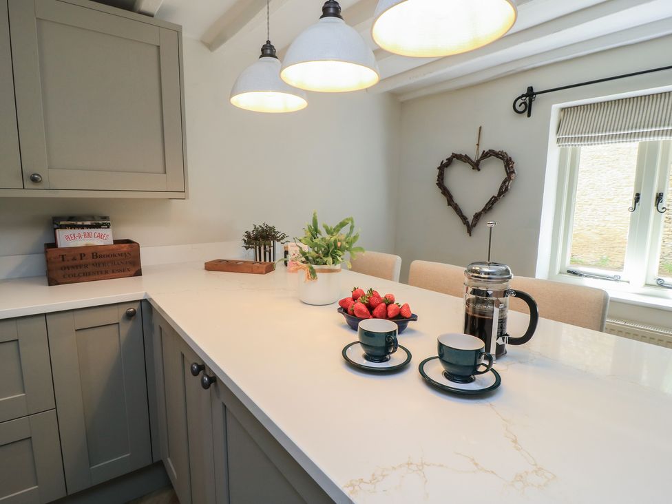A kitchen with a counter, coffee maker, cups, and strawberries at 2 The Gardens in Lechlade