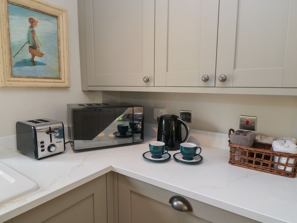 A kitchen with appliances and tea cups at 2 The Gardens Lechlade
