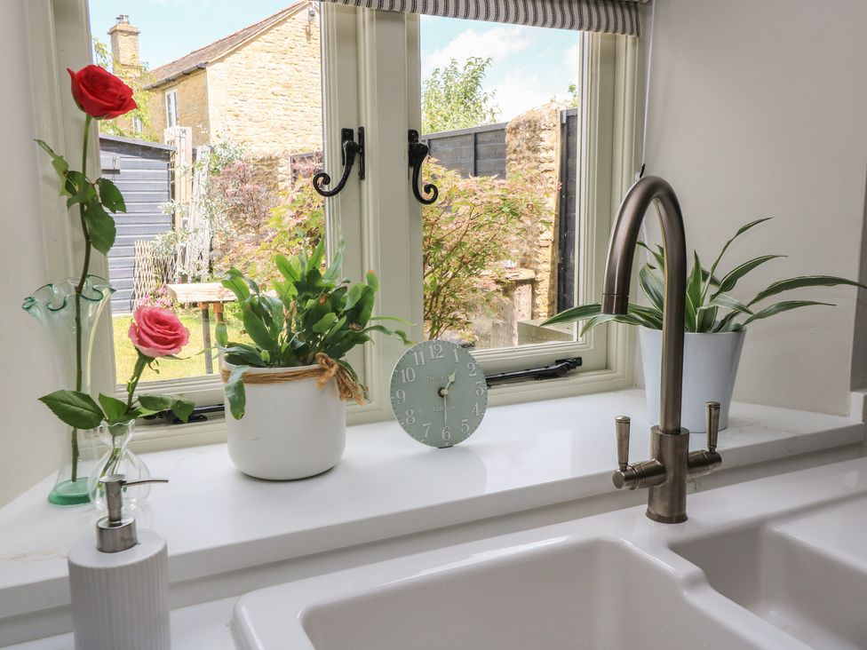 A kitchen with a view of a garden and decorative items at 2 The Gardens Lechlade