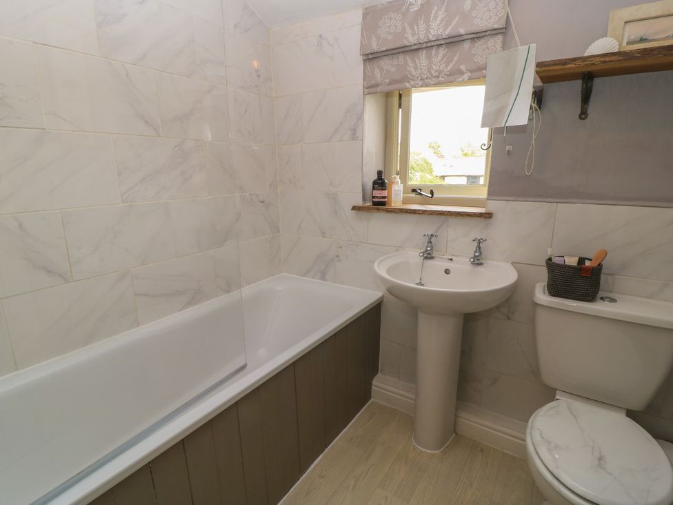 A bathroom with a bathtub, sink, and toilet at 2 The Gardens Lechlade