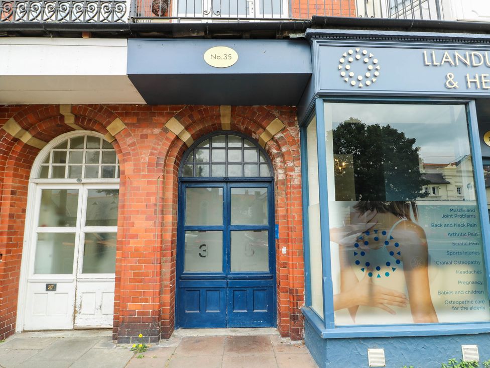 The entrance of a building with a blue door and signage at Flat 3 in Llandudno