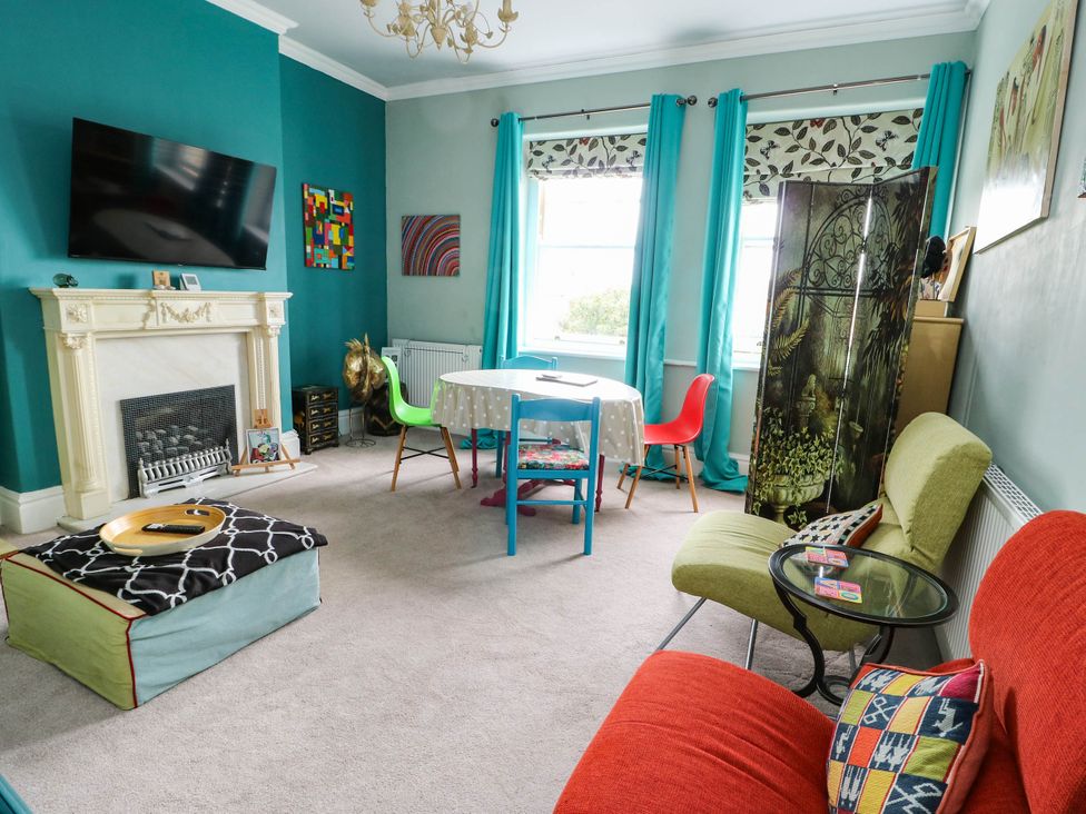 A living room with a television, table, and seating area at Flat 3 in Llandudno