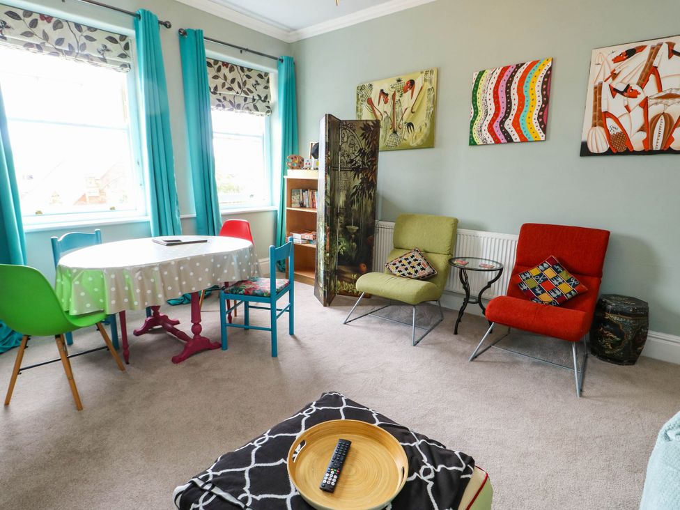 A living room with a table and colorful chairs at Flat 3 in Llandudno