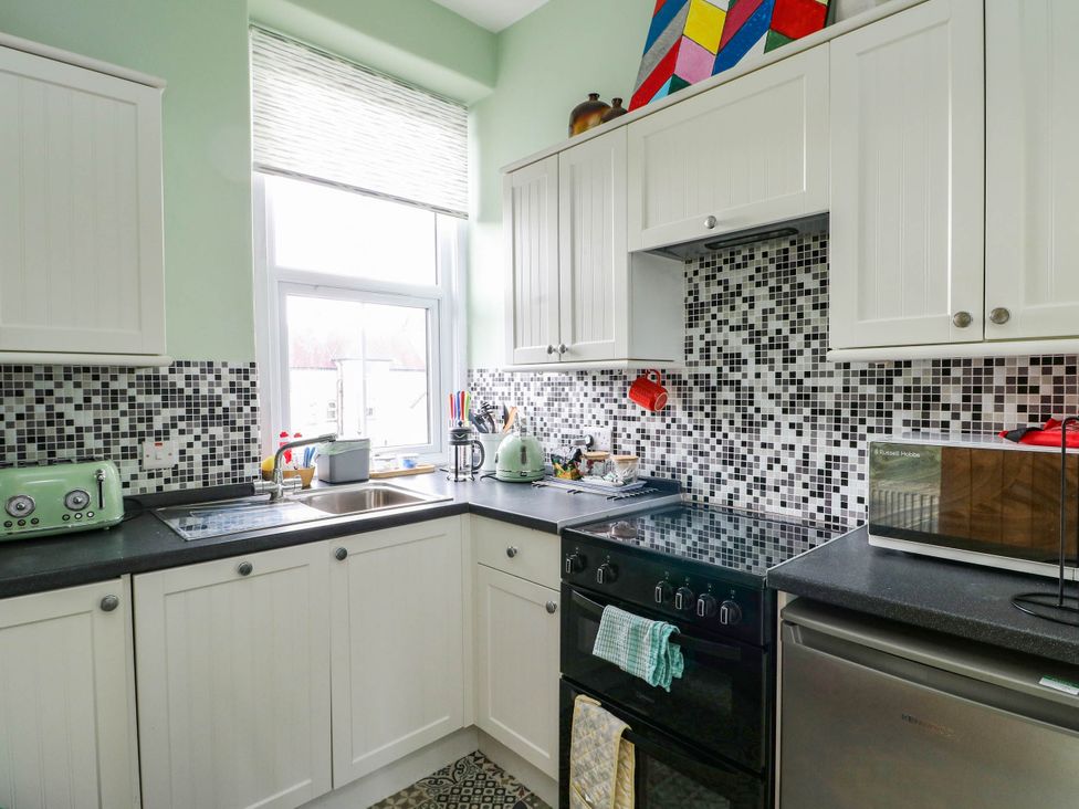A kitchen with a sink and appliances at Flat 3 in Llandudno