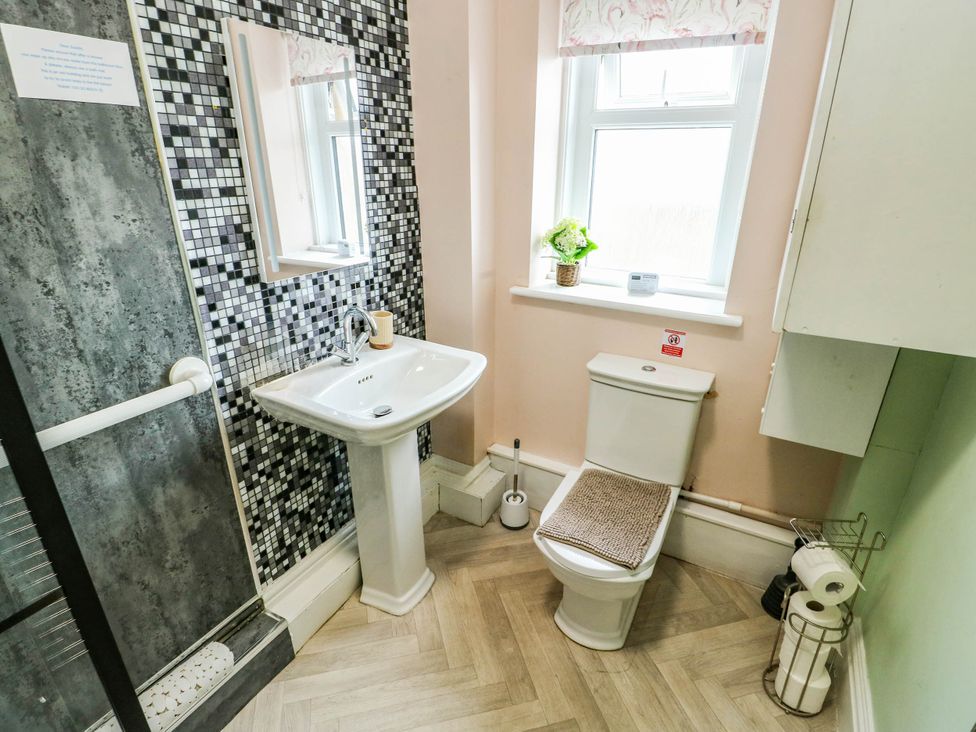 A bathroom with a shower, hand basin, and toilet at Flat 3 in Llandudno