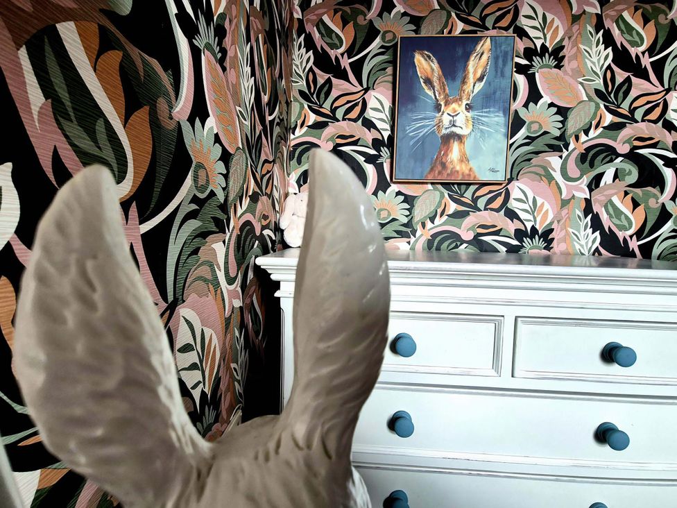 A bedroom with a rabbit statue and floral wallpaper at Flat 3 in Llandudno