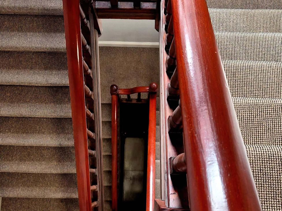 A staircase with a wooden handrail and carpet at Flat 3 in Llandudno