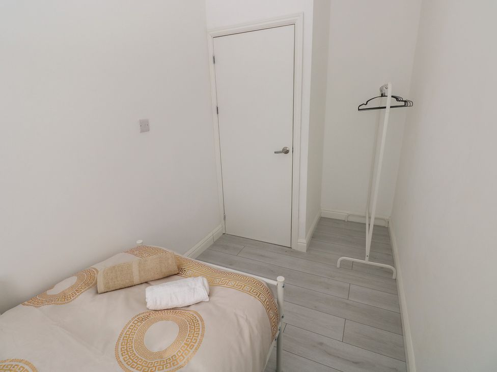 A bedroom with a bed and a clothes rack at 5 Gelli Terrace in Caerphilly