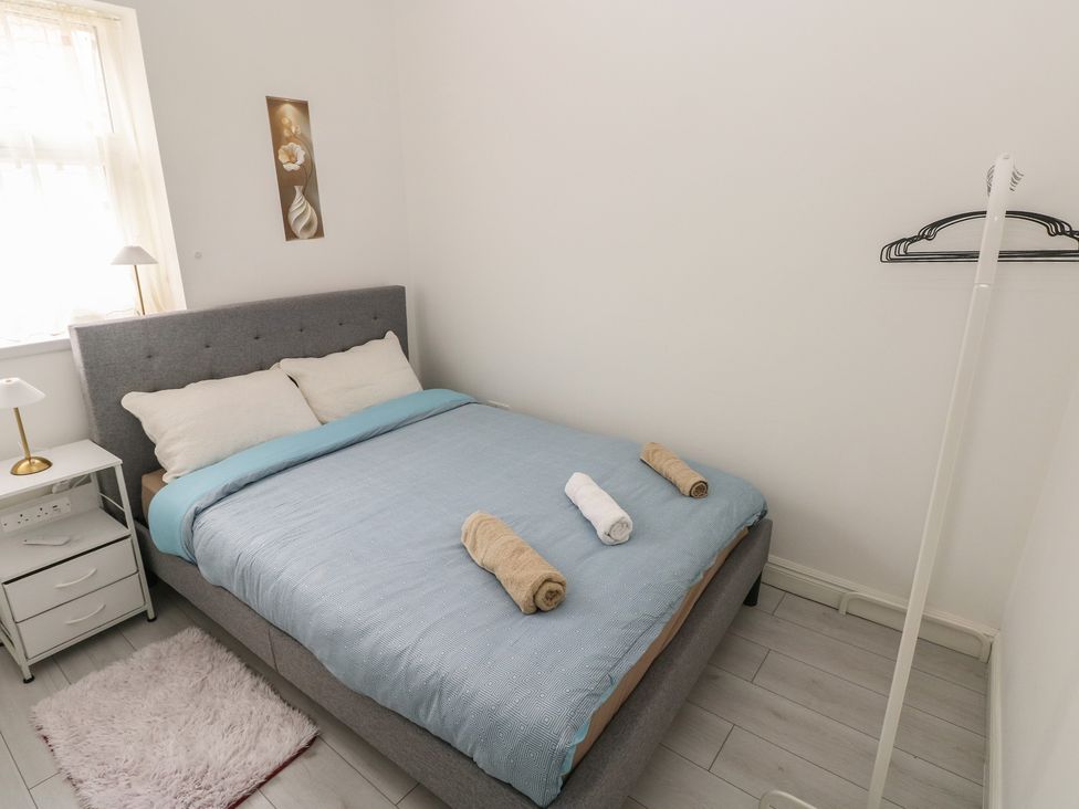 A bedroom with a bed, nightstand, lamp, and towels at 5 Gelli Terrace in Caerphilly