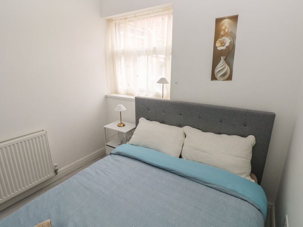 A bedroom with a bed and a table lamp at 5 Gelli Terrace in Caerphilly