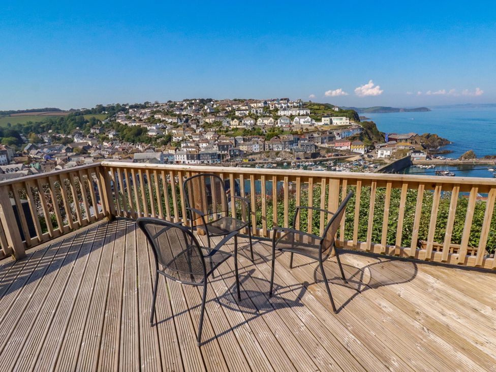 A deck with chairs and a table overlooking the harbor at Trewollock in Mevagissey