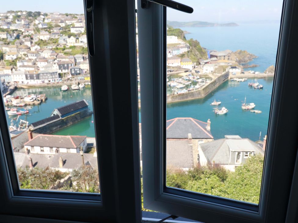 A view from a window overlooking a harbor with boats at Trewollock in Mevagissey
