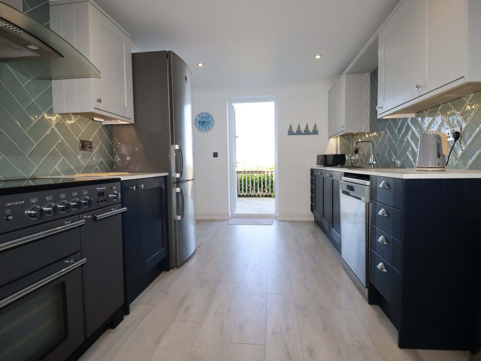 A kitchen with an oven, refrigerator, and sink at Trewollock in Mevagissey