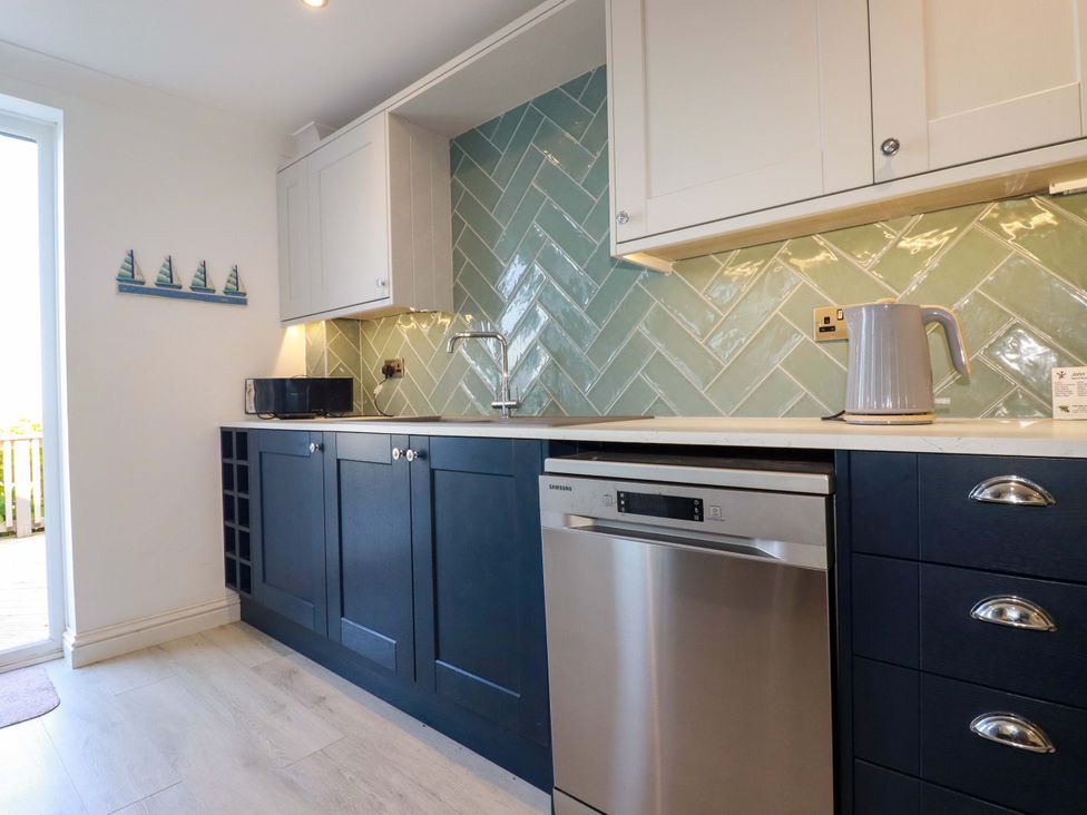 A kitchen with a sink, microwave, and dishwasher at Trewollock in Mevagissey
