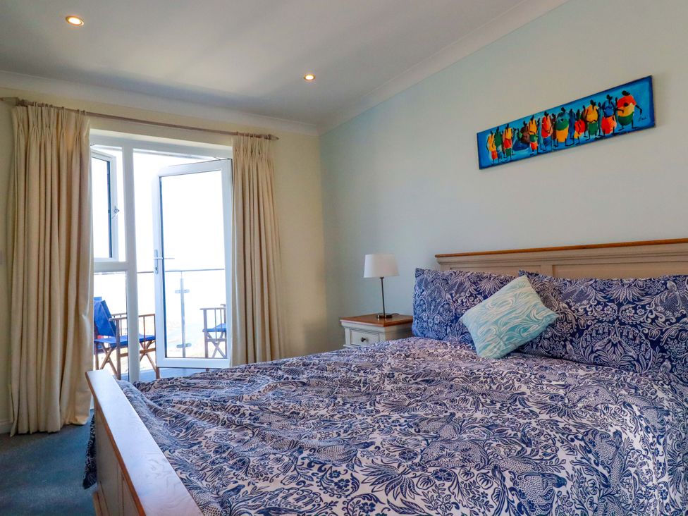A bedroom with a bed and a balcony door at Trewollock in Mevagissey